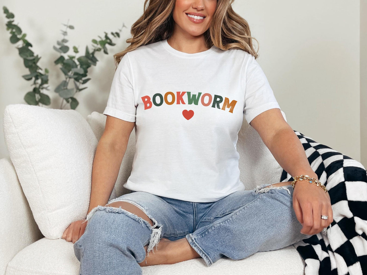 a woman sitting on a couch wearing a book worm t - shirt