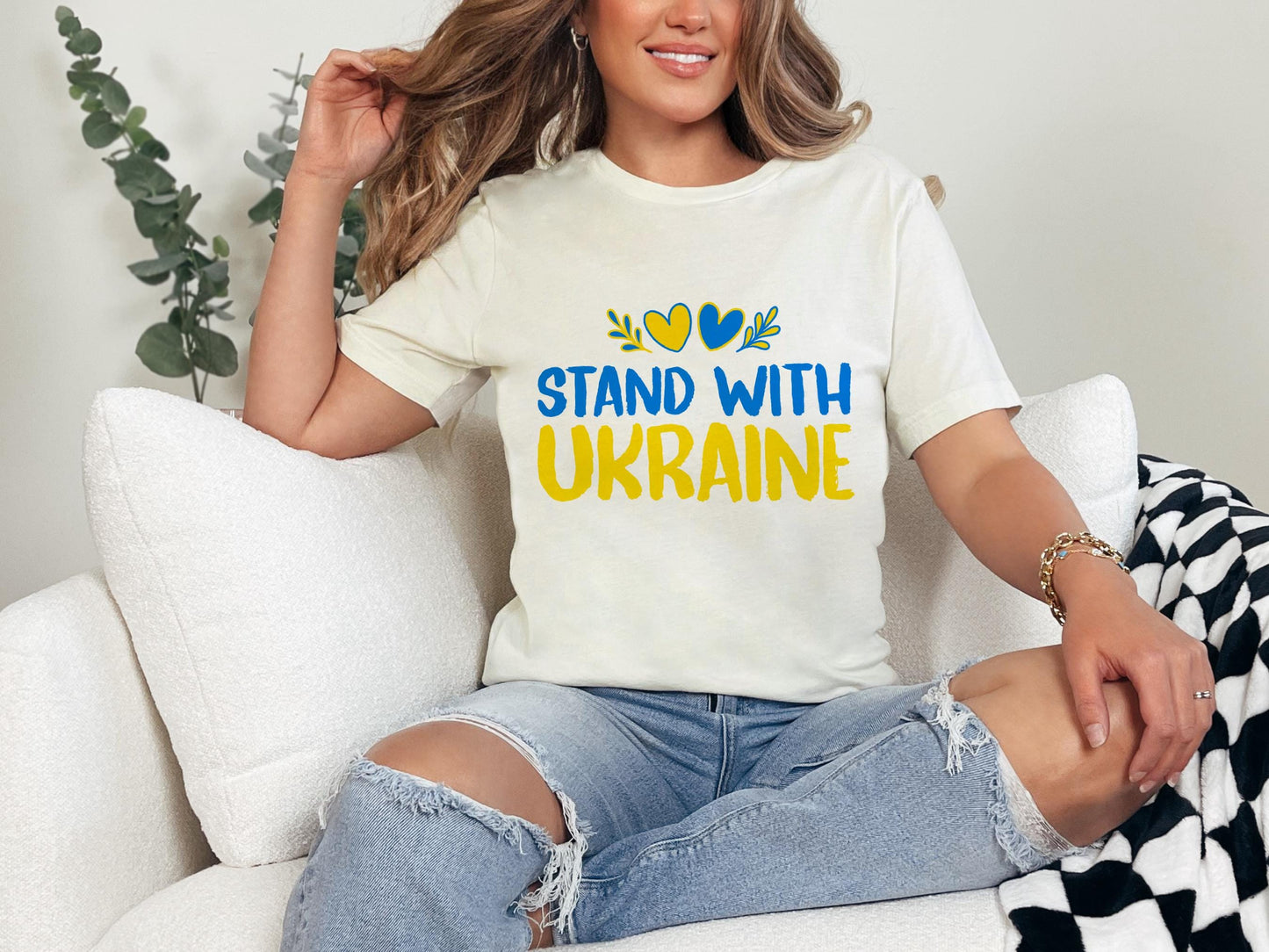 a woman sitting on a couch wearing a t - shirt that says stand with ukraine