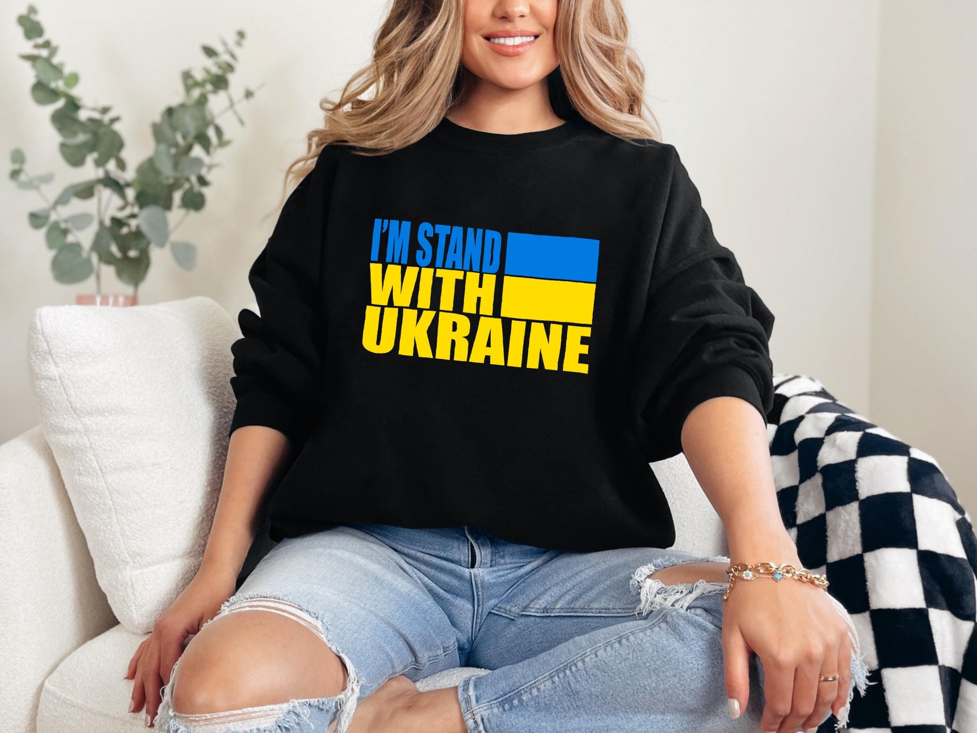 a woman sitting on a couch wearing a black sweatshirt that says i&#39;m stand