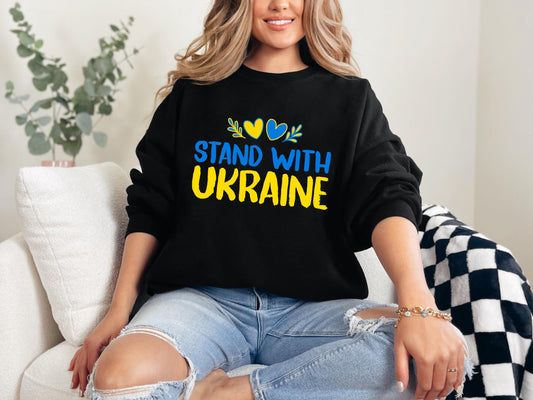 a woman sitting on a couch wearing a black sweatshirt with the words stand with ukraine