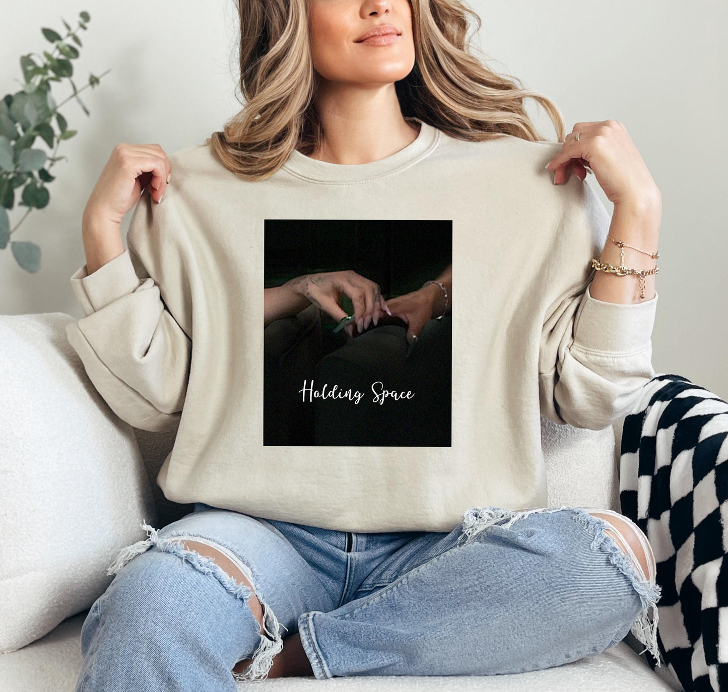 a woman sitting on a couch holding up a t - shirt