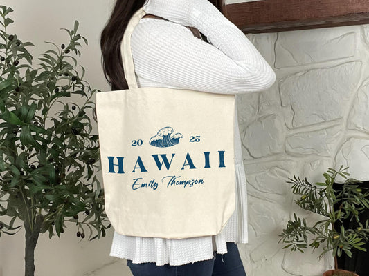 a woman holding a tote bag with the words hawaii on it