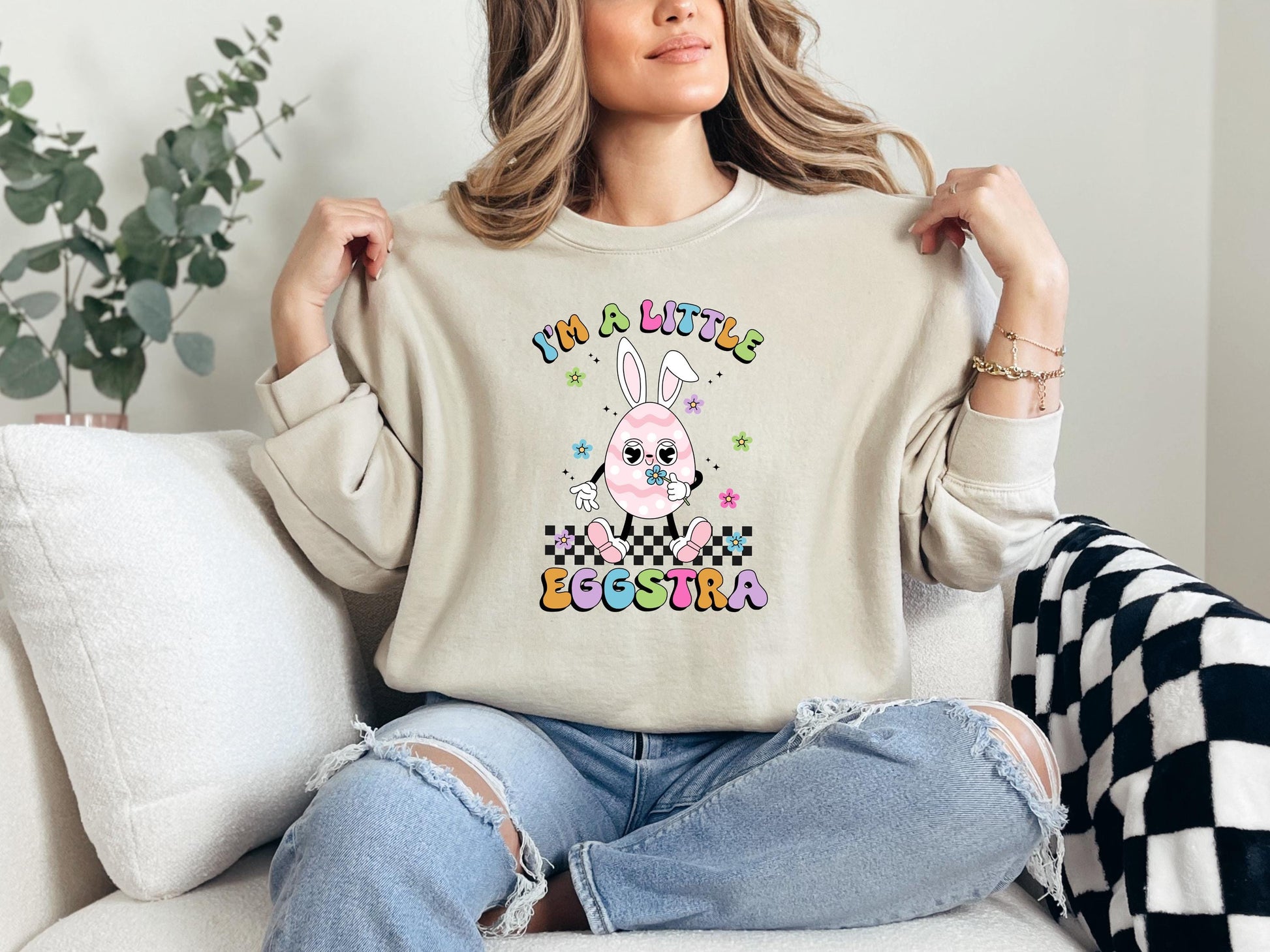 a woman sitting on a couch holding up a t - shirt