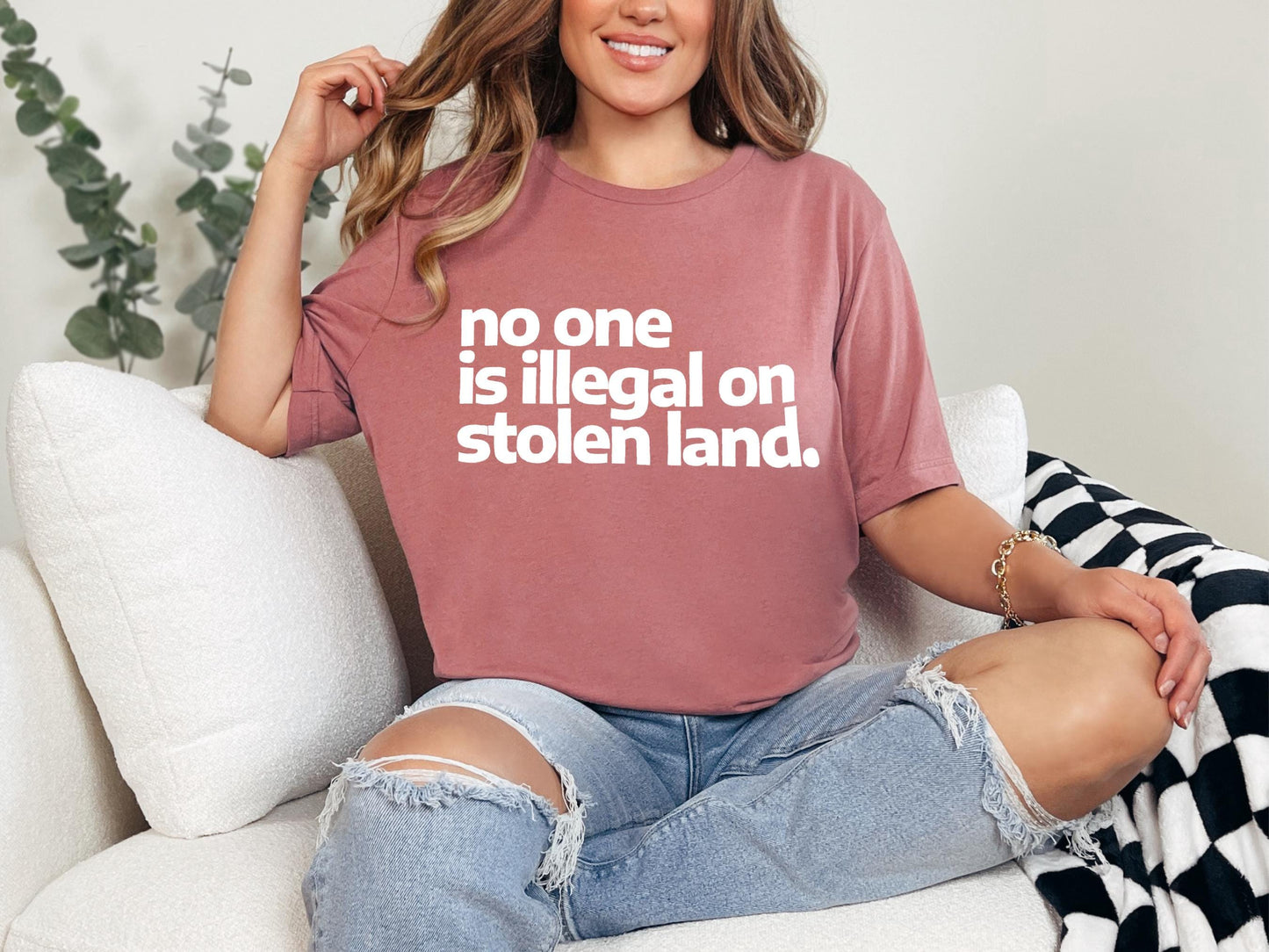 a woman sitting on a couch wearing a t - shirt that says no one is
