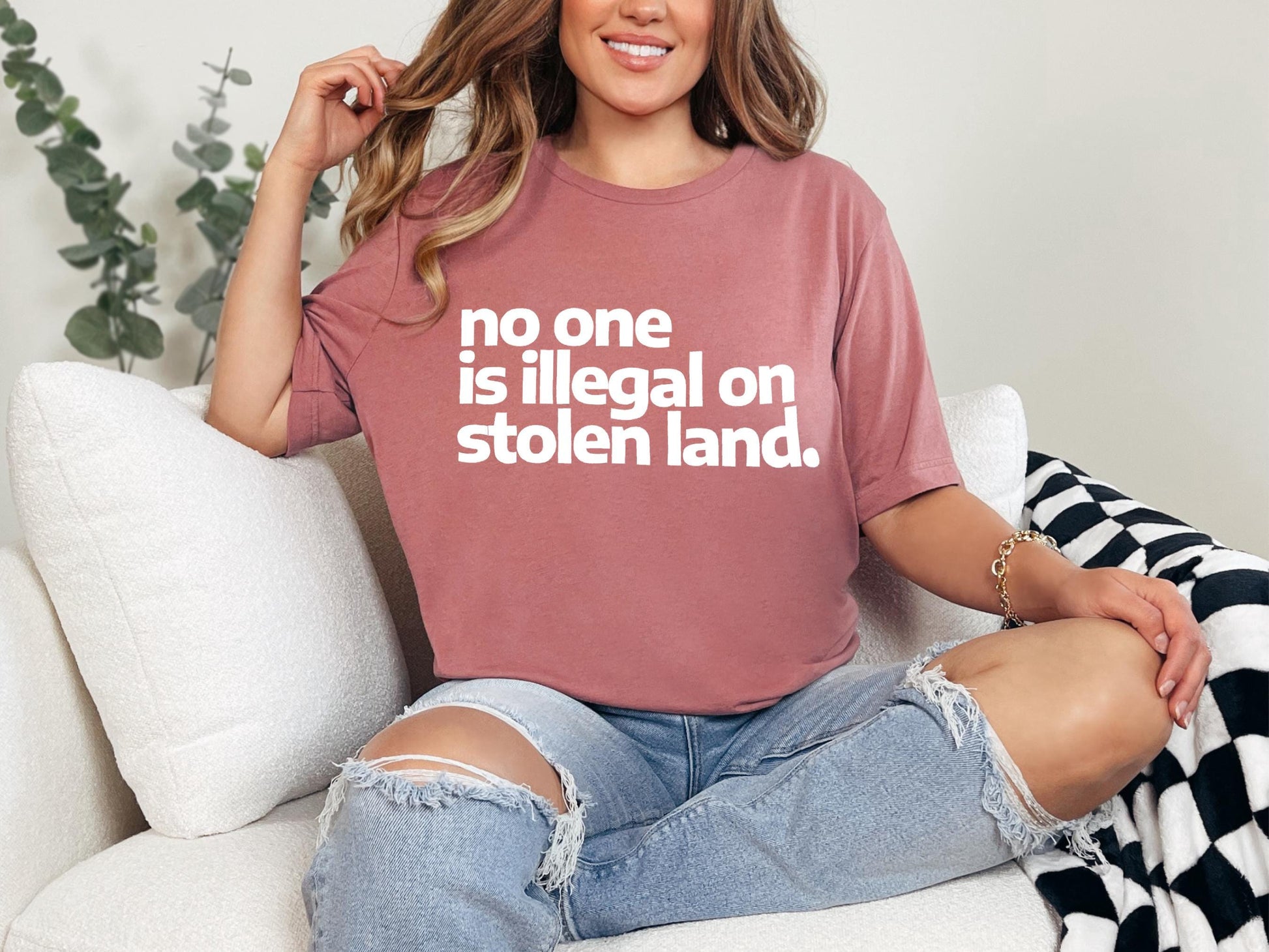 a woman sitting on a couch wearing a t - shirt that says no one is