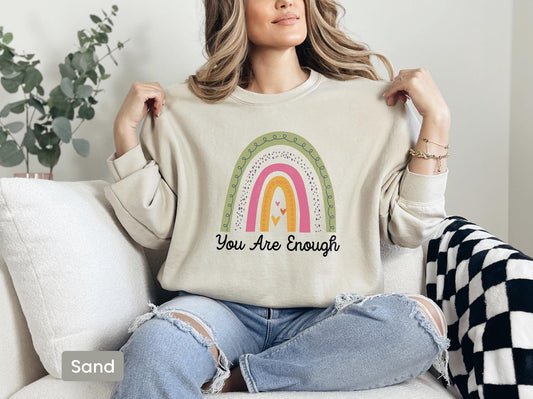 a woman sitting on a couch holding a t - shirt that says you are enough