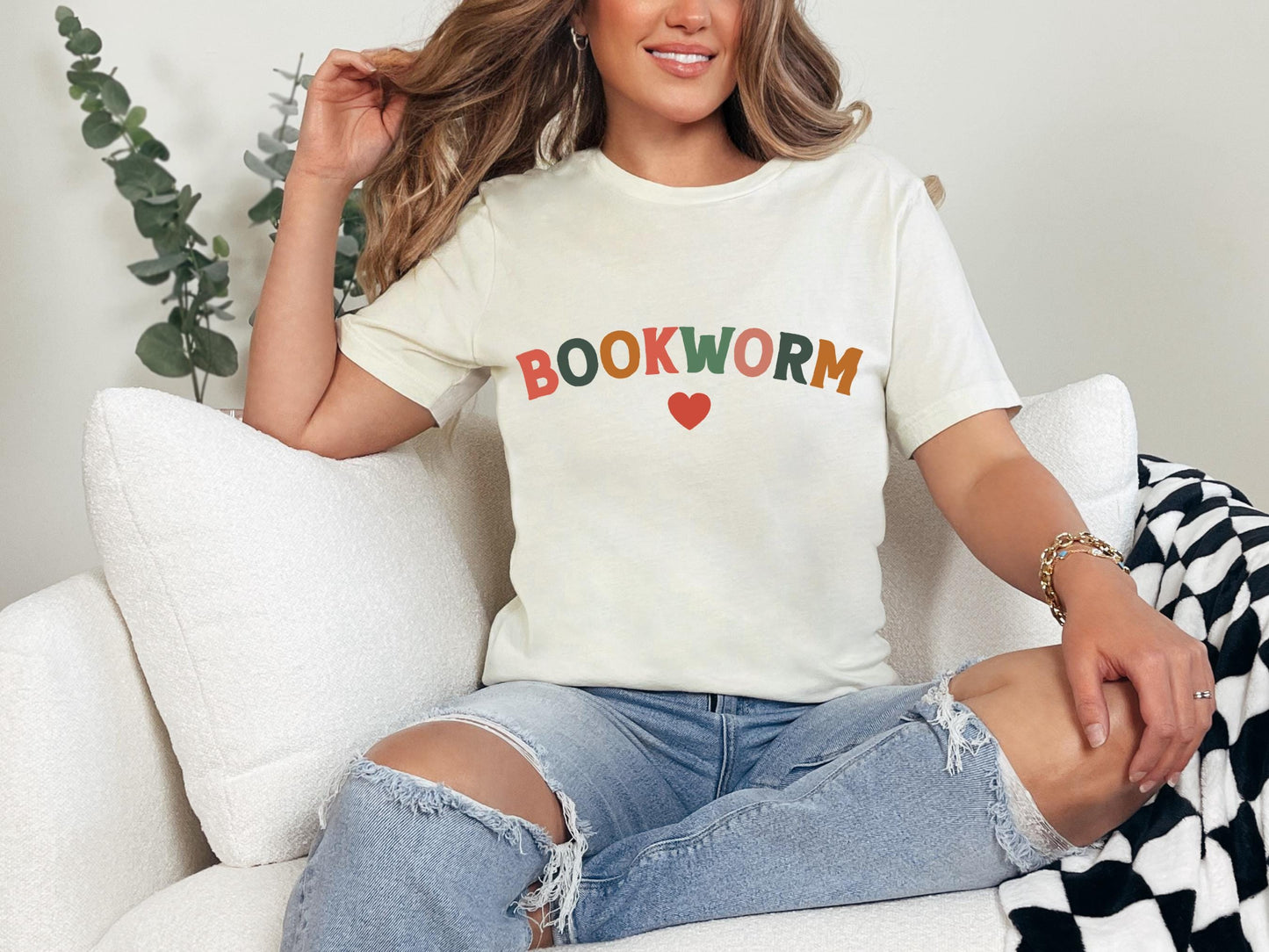 a woman sitting on a couch wearing a book worm t - shirt
