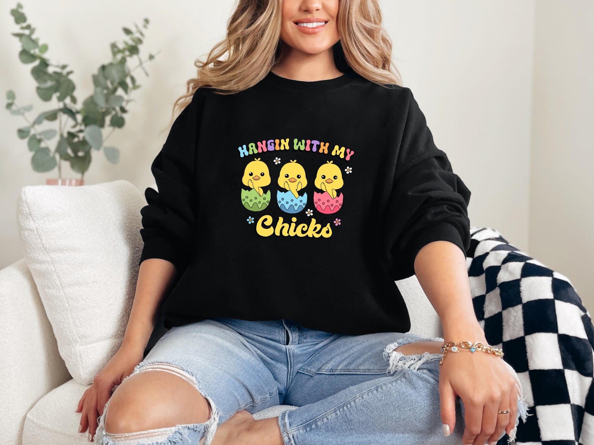 a woman sitting on a couch wearing a black sweatshirt