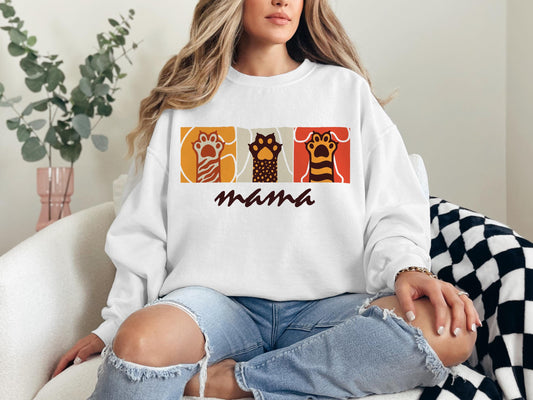 a woman sitting on a couch wearing a sweatshirt that says mama