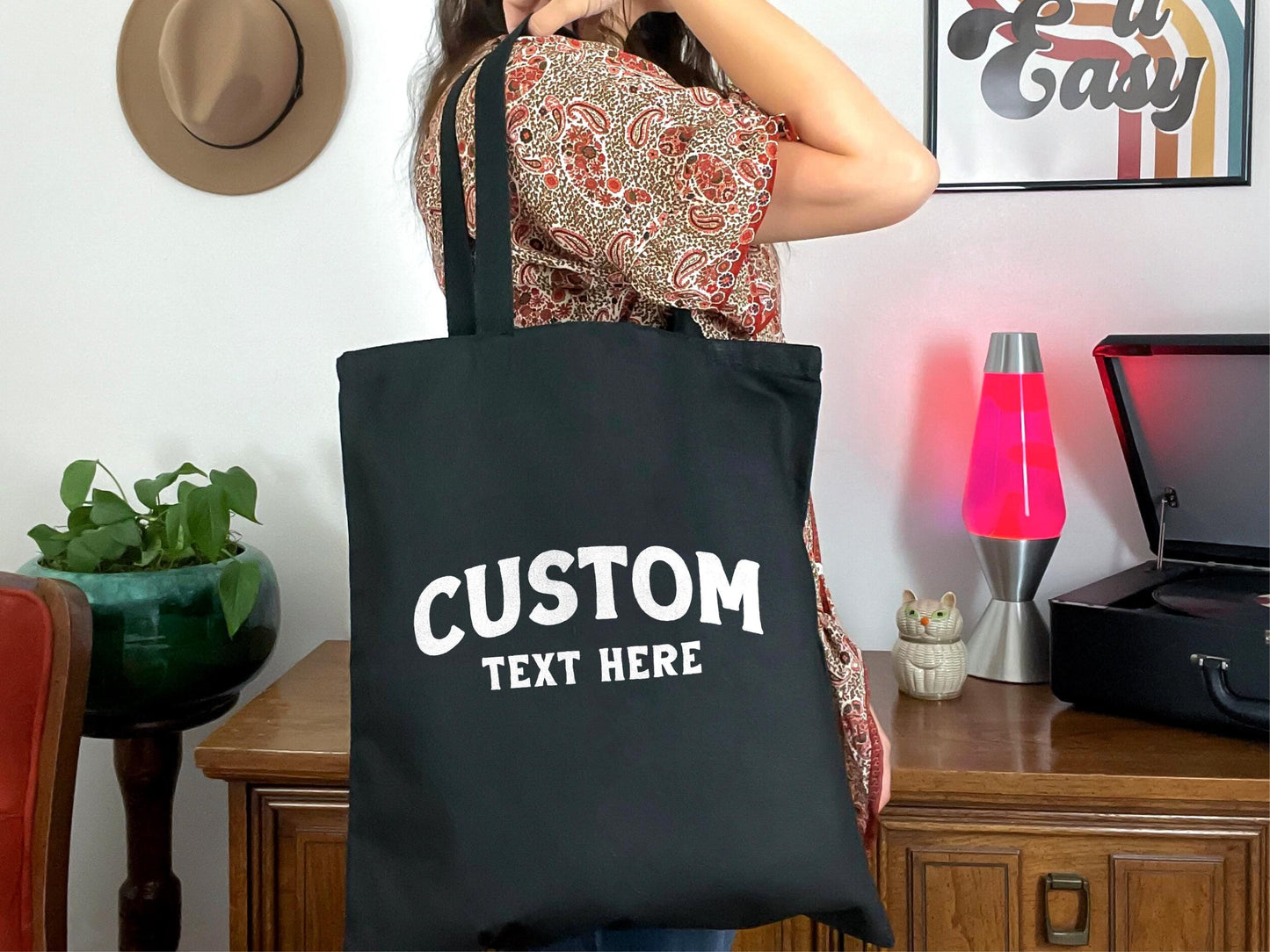 a woman holding a black tote bag with custom text