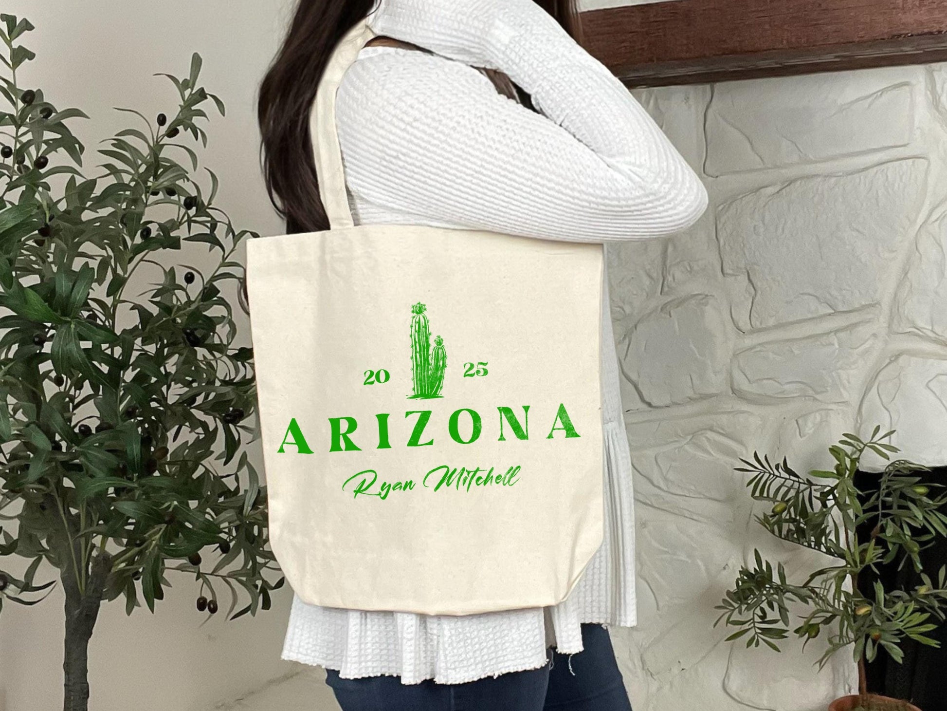 a woman holding a tote bag with a cactus on it