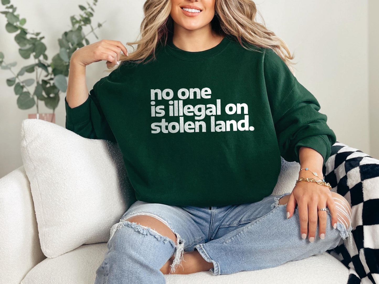 a woman sitting on a couch wearing a green sweatshirt