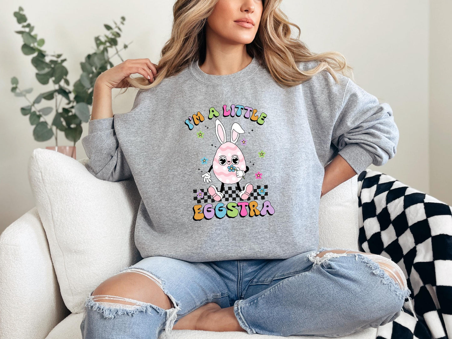 a woman sitting on a couch wearing a sweatshirt with a bunny on it
