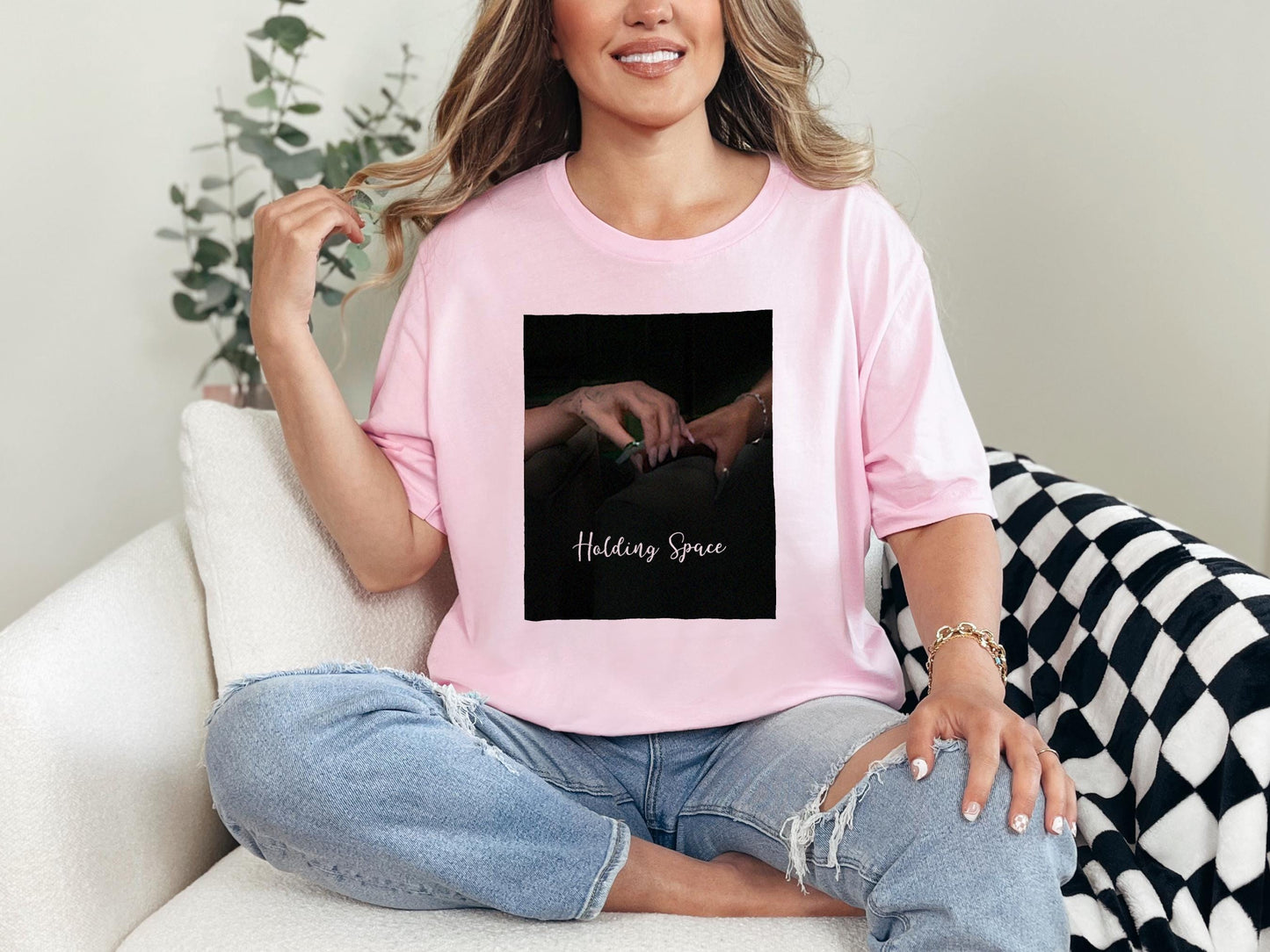 a woman sitting on a white couch wearing a pink t - shirt