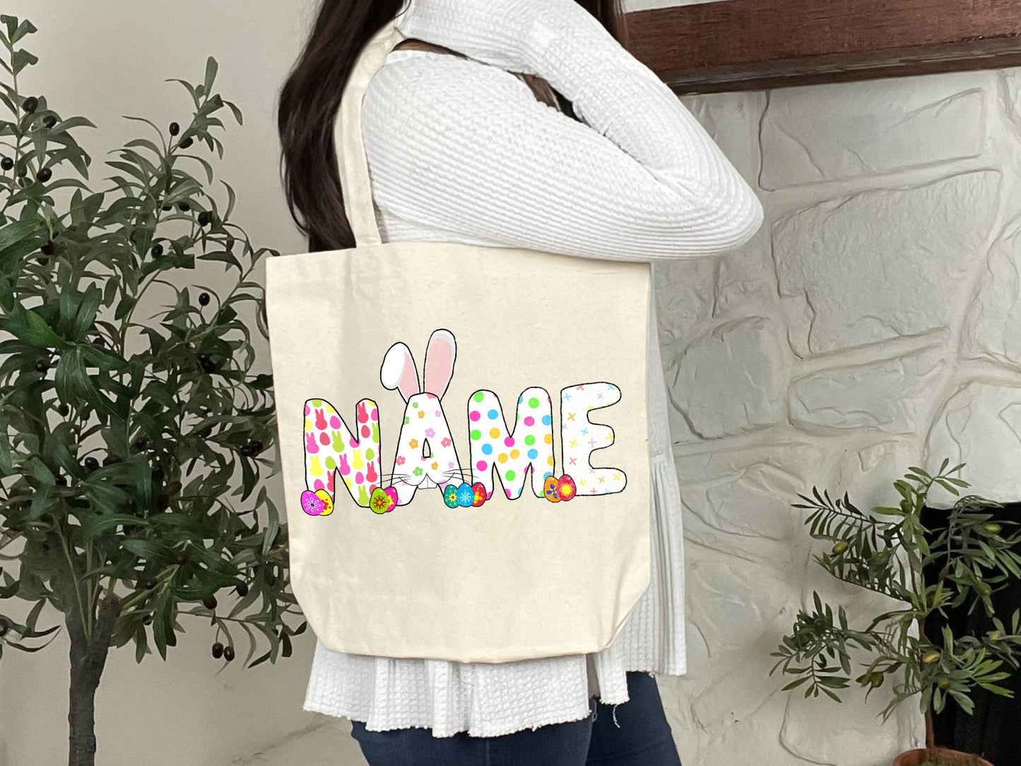 a woman holding a tote bag with the word name painted on it