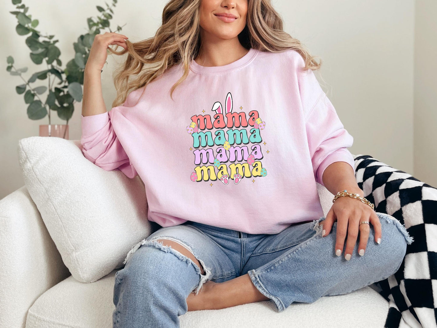 a woman sitting on a couch wearing a pink sweatshirt
