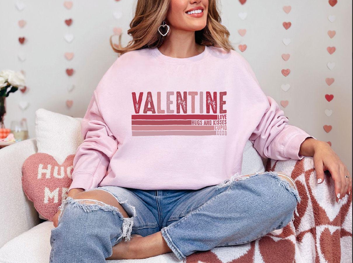 a woman sitting on a couch wearing a pink sweater