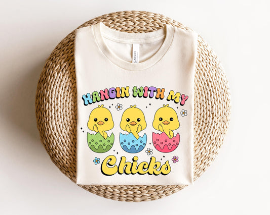 a white t - shirt with a picture of three chicks on it