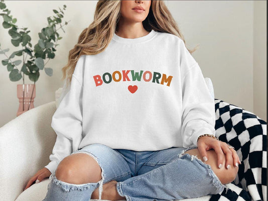 a woman sitting on a couch wearing a book worm sweatshirt