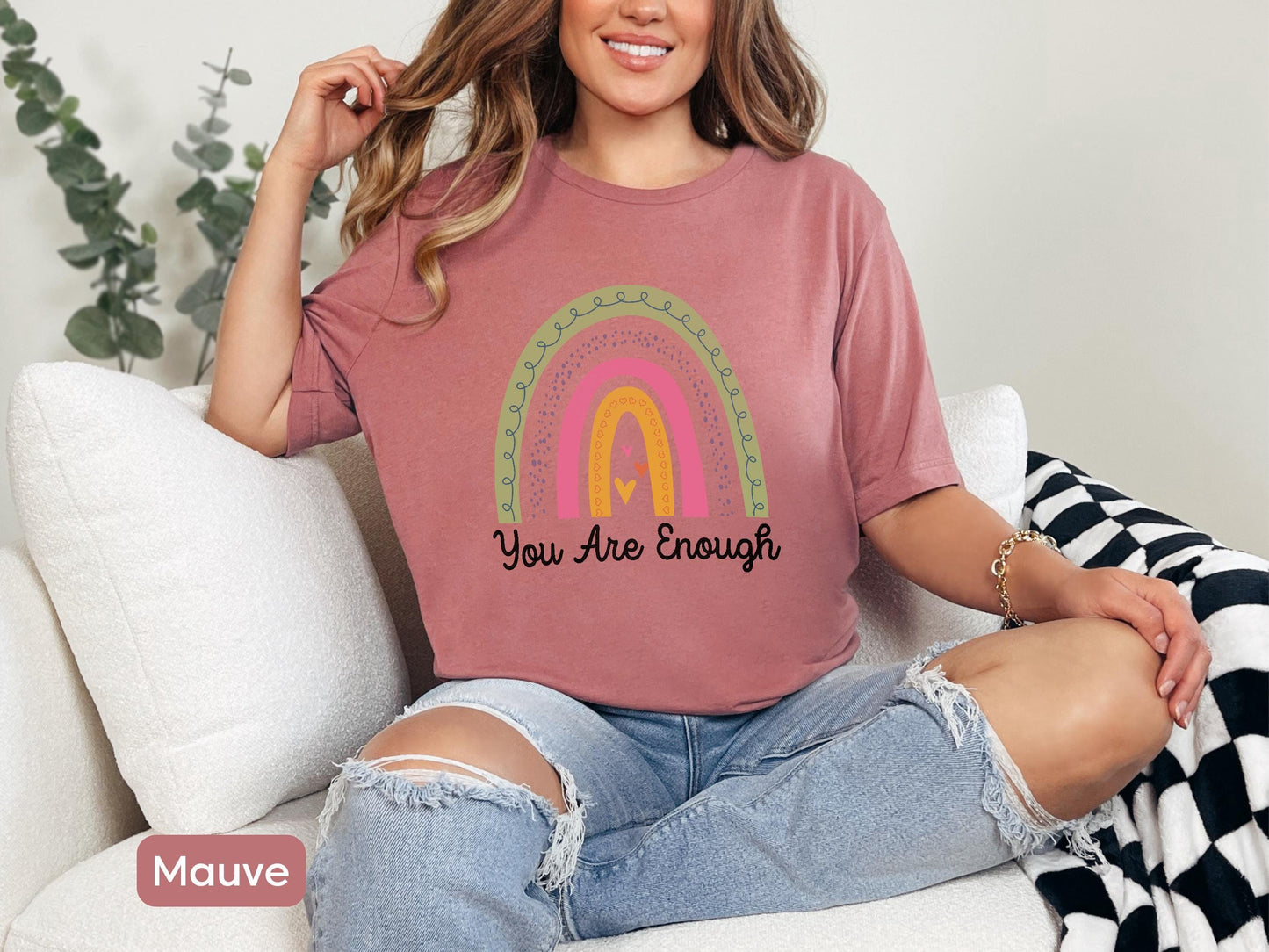 a woman sitting on a couch wearing a t - shirt that says you are enough