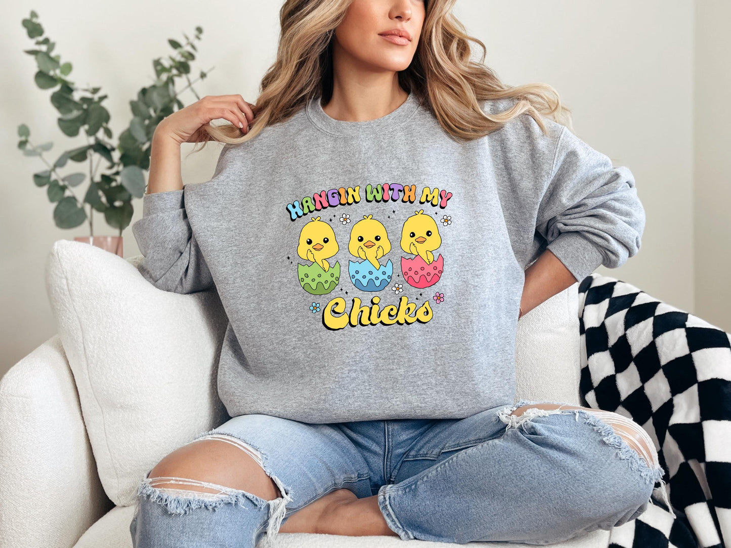 a woman sitting on a couch wearing a gray sweatshirt