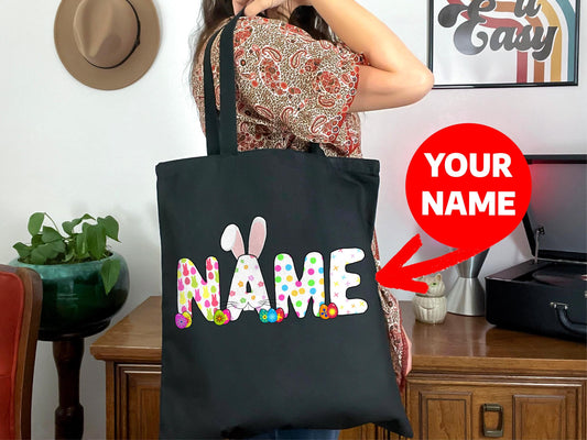 a woman holding a black bag with a name on it