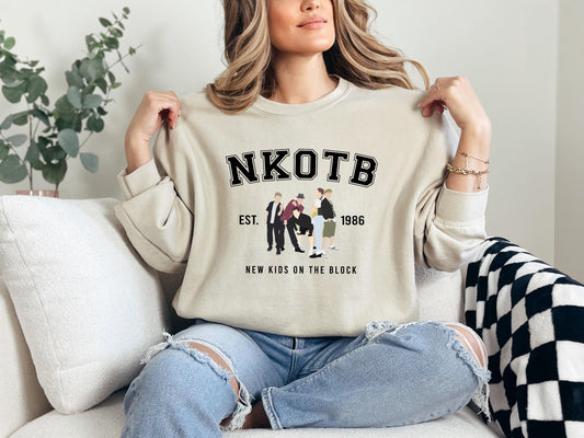 a woman sitting on a couch holding up a sweater