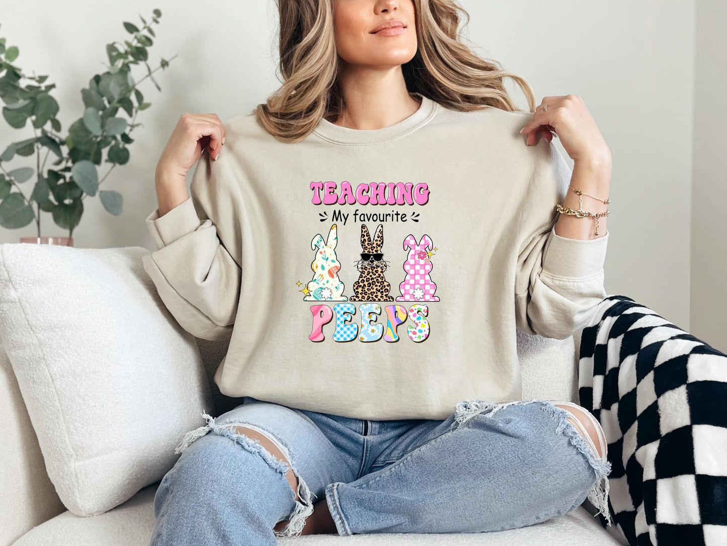 a woman sitting on a couch holding up a t - shirt