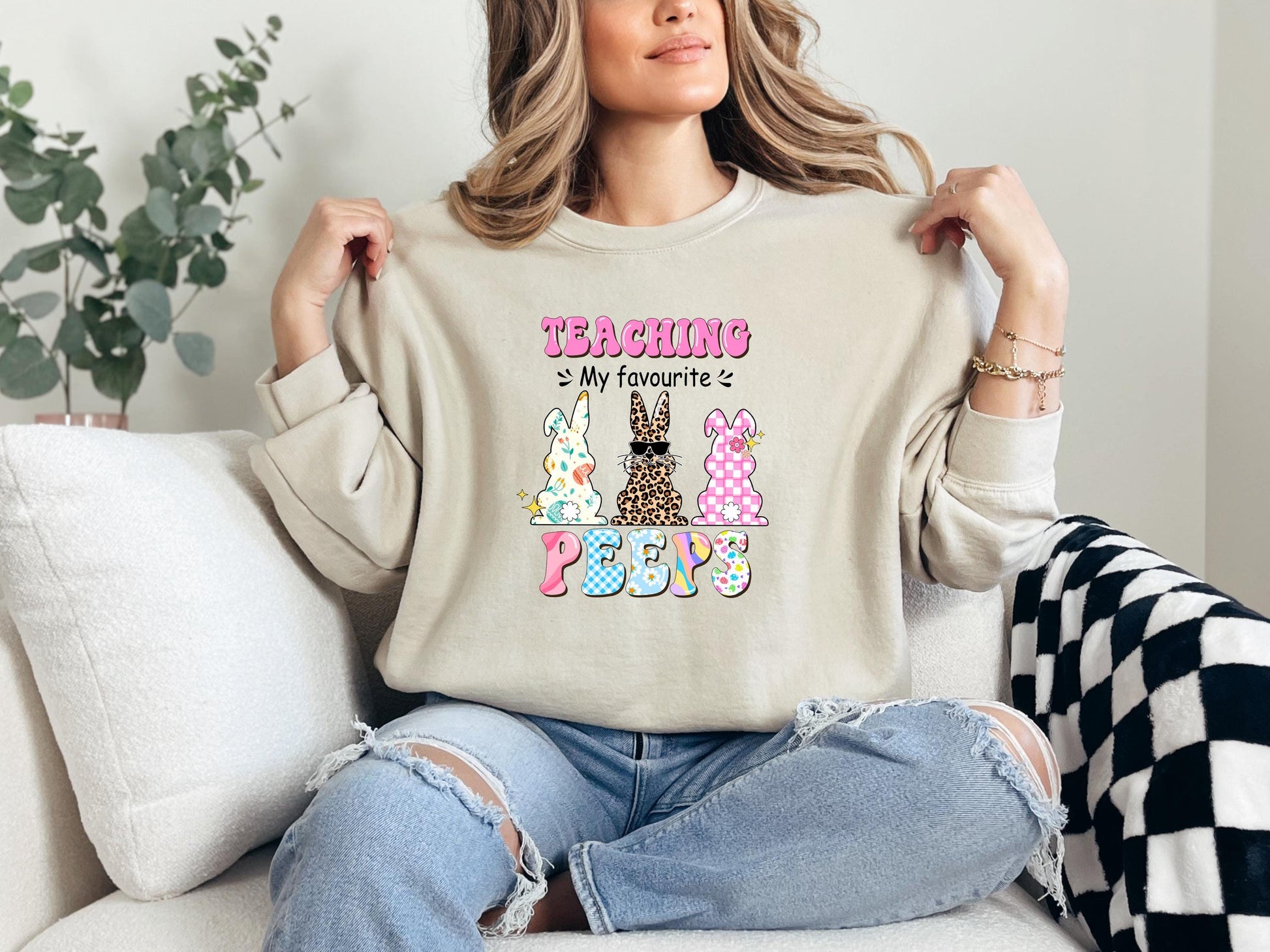 a woman sitting on a couch holding up a t - shirt