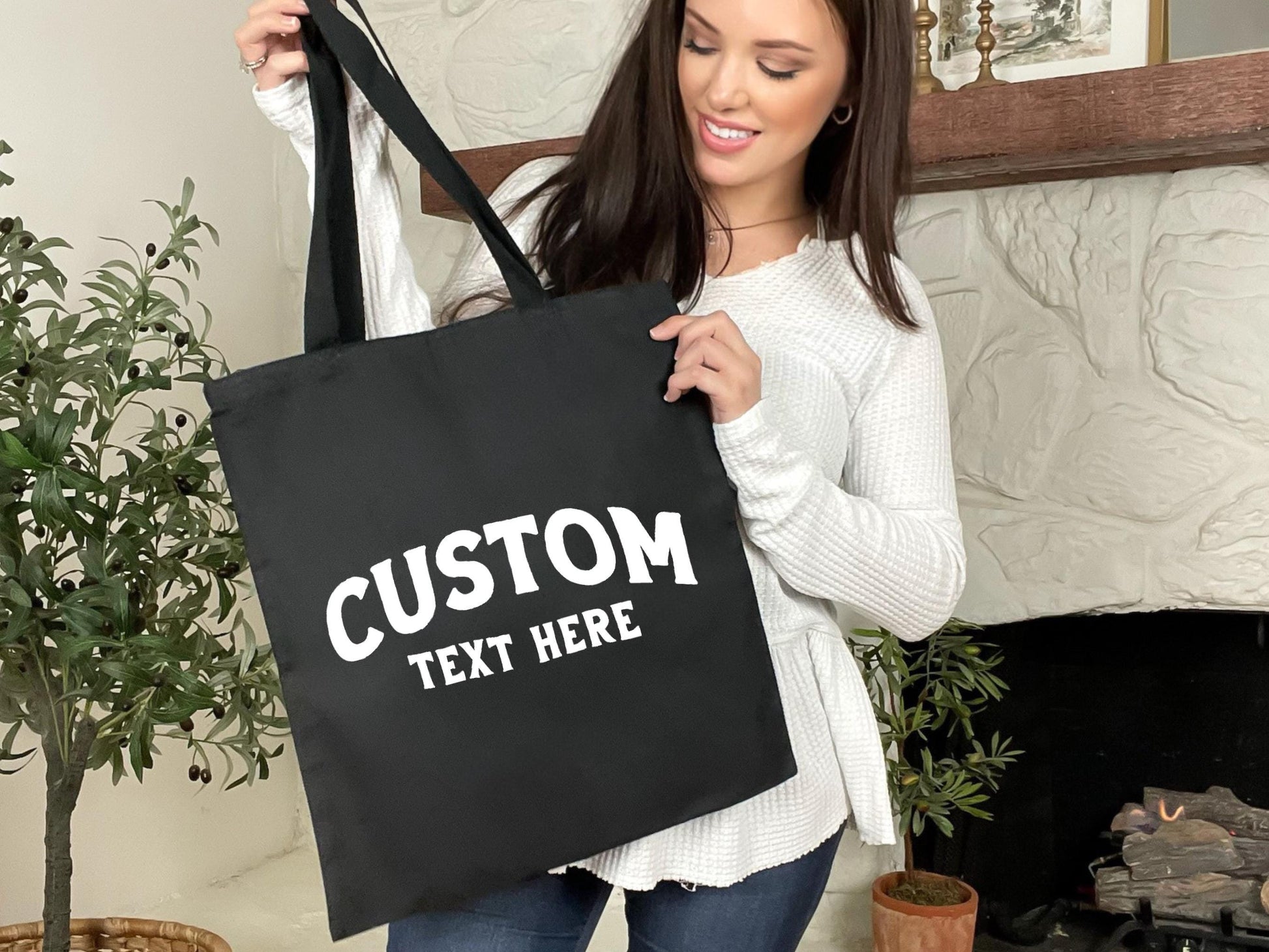 a woman holding a black tote bag with custom text