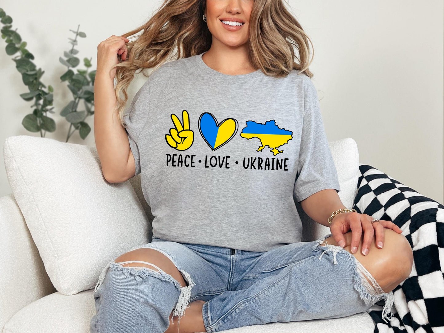a woman sitting on a couch wearing a peace love ukraine shirt