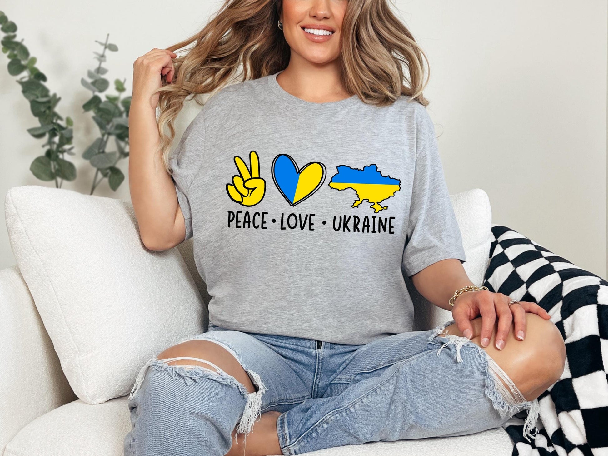 a woman sitting on a couch wearing a peace love ukraine shirt