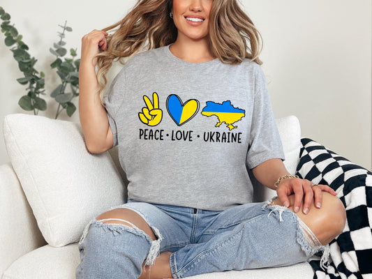 a woman sitting on a couch wearing a peace love ukraine shirt